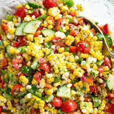 Fresh corn salad with colorful vegetables and dressing on a plate