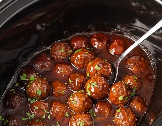 Slow Cooker Bourbon Meatballs simmering in a bourbon glaze sauce.
