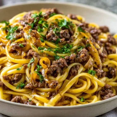 Plate of Garlic Butter Beef Pasta garnished with herbs and parmesan cheese