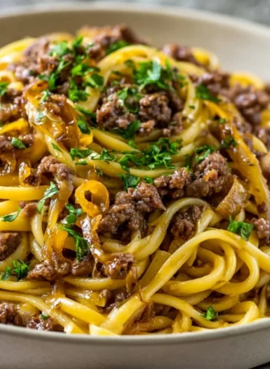 Plate of Garlic Butter Beef Pasta garnished with herbs and parmesan cheese