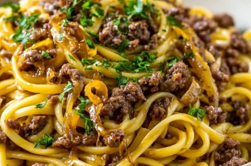 Plate of Garlic Butter Beef Pasta garnished with herbs and parmesan cheese
