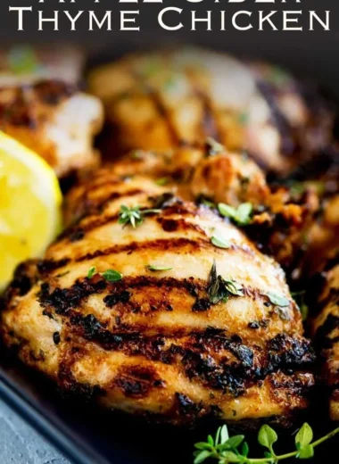 Grilled apple cider thyme chicken garnished with herbs and served on a plate