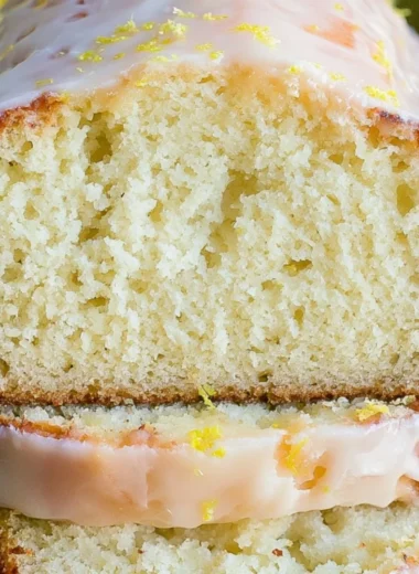Moist lemon pound cake with a zesty lemon glaze on a white plate.