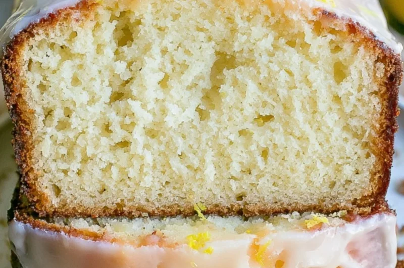 Moist lemon pound cake with a zesty lemon glaze on a white plate.