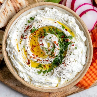 Delicious whipped feta dip served in a bowl with herbs and crackers.
