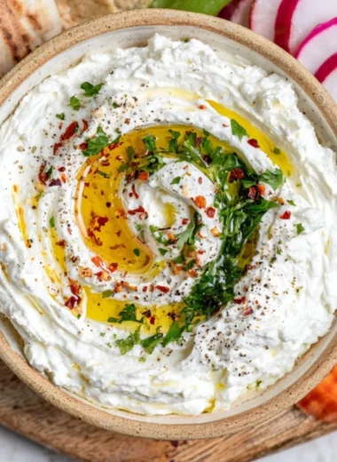 Delicious whipped feta dip served in a bowl with herbs and crackers.