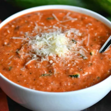 Bowl of fresh zucchini tomato soup garnished with herbs.