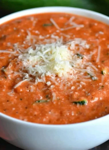 Bowl of fresh zucchini tomato soup garnished with herbs.