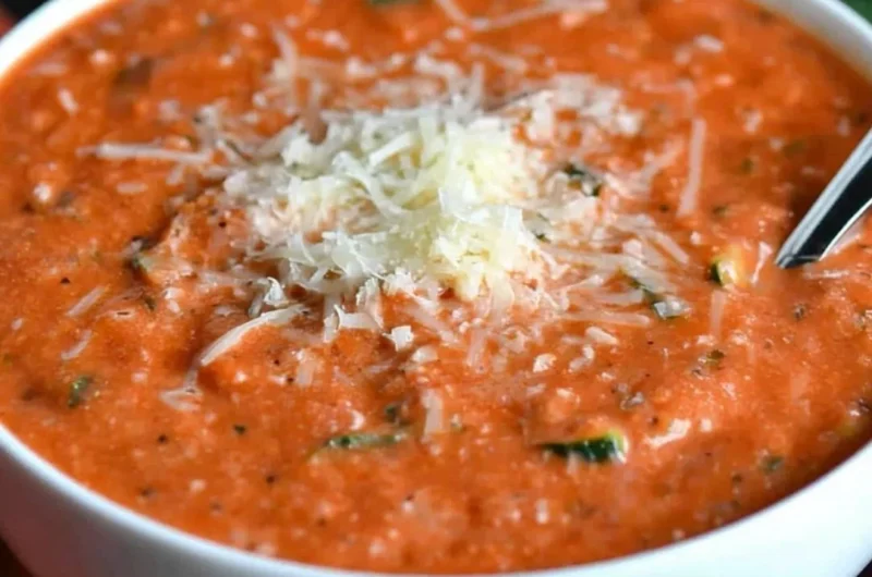 Bowl of fresh zucchini tomato soup garnished with herbs.