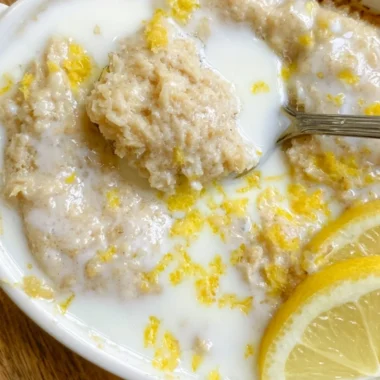 Bowl of cozy lemon baked oats topped with fresh lemon zest and berries.