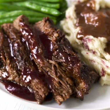 Delicious Crock Pot Chuck Roast served with vegetables and herbs