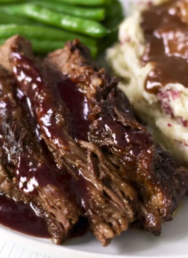 Delicious Crock Pot Chuck Roast served with vegetables and herbs