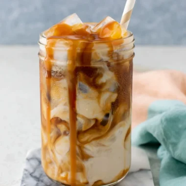 Homemade caramel iced coffee in a glass with ice and whipped cream topping