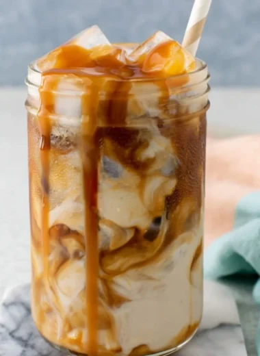 Homemade caramel iced coffee in a glass with ice and whipped cream topping