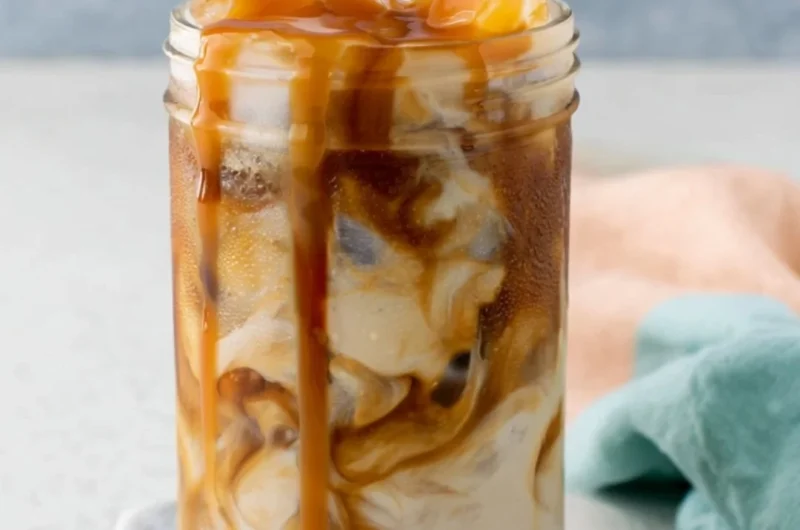 Homemade caramel iced coffee in a glass with ice and whipped cream topping