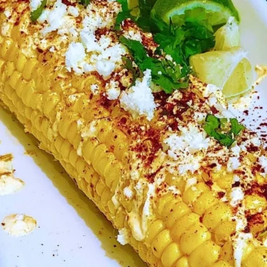 Delicious Mexican corn elotes topped with cheese and chili powder.