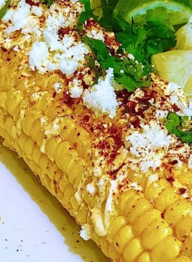 Delicious Mexican corn elotes topped with cheese and chili powder.