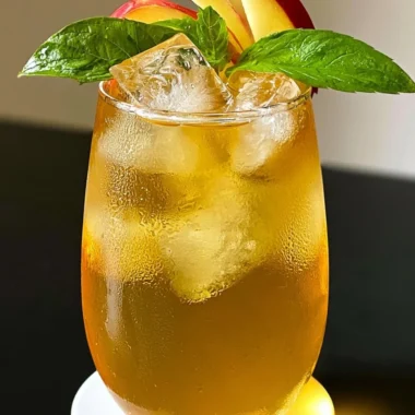 Glass of refreshing iced apple green tea with apple slices and mint leaves