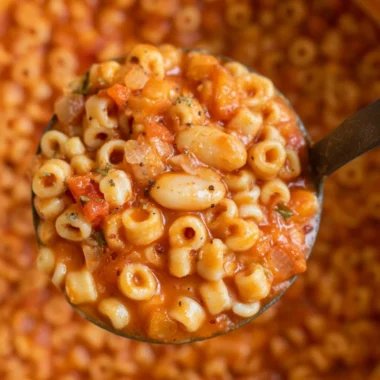 Bowl of hearty Pasta Fagioli soup topped with herbs and served with crusty bread.