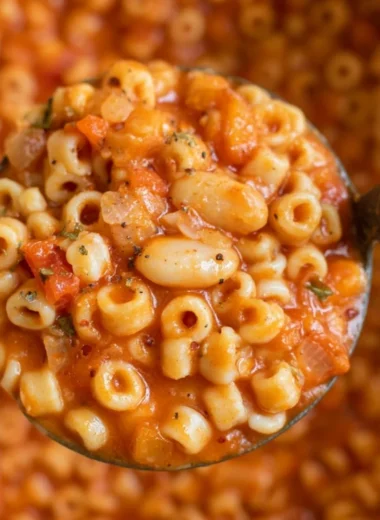 Bowl of hearty Pasta Fagioli soup topped with herbs and served with crusty bread.